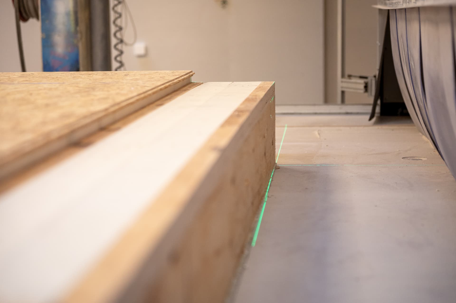 Close-up of a robot-machined timber element with a green laser line for precise measurement